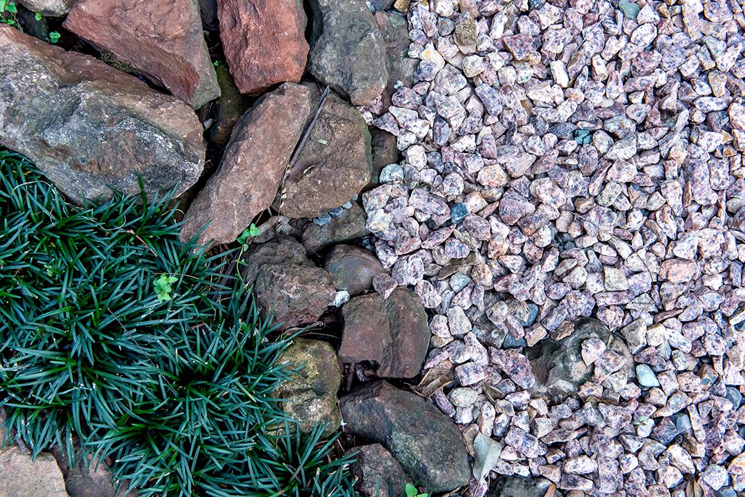 Fundo de canteiro de flores com pedras e grama.