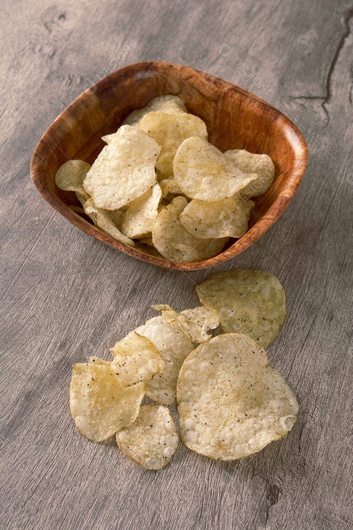 Batatas fritas em uma tigela de madeira sobre fundo de madeira