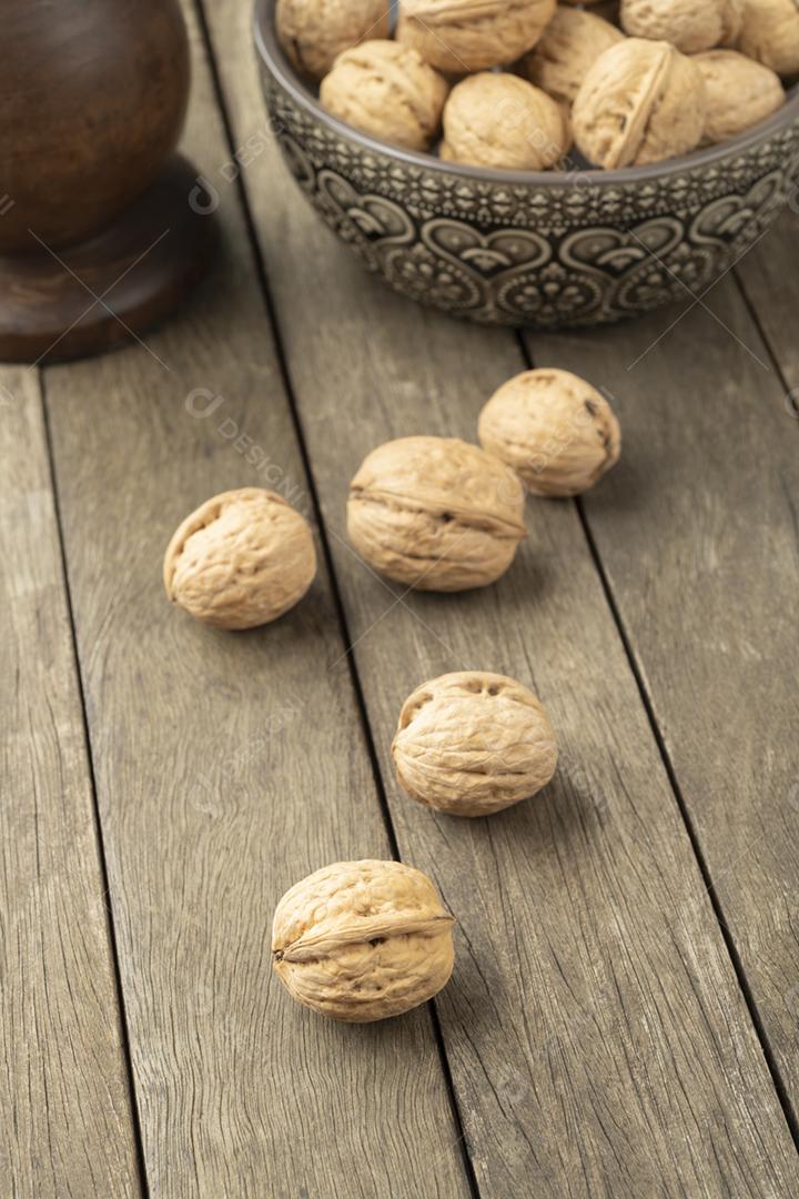 Nozes sobre uma mesa de madeira e em uma tigela