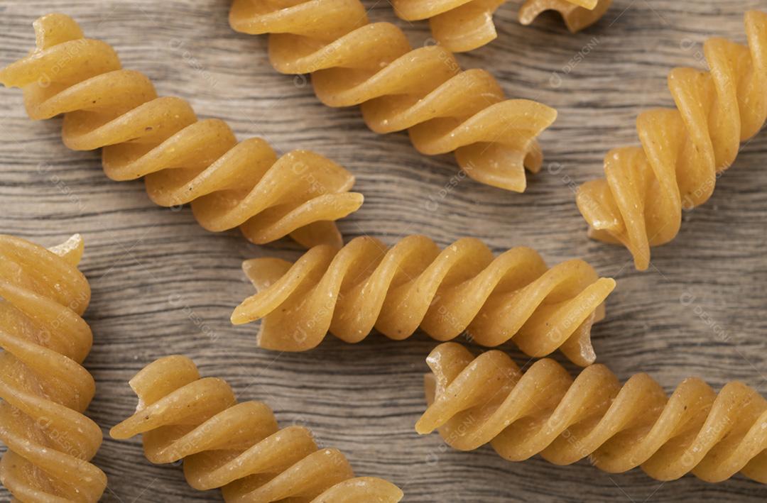 Closeup de foco estreito de macarrão fusilli de trigo integral sobre ta de madeira