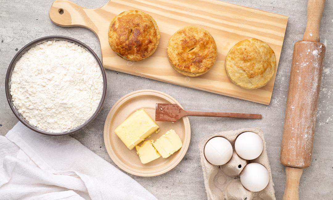 Tortas caseiras sobre placa de madeira com ingredientes