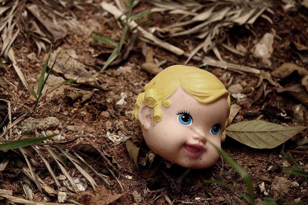 Cabeça de boneca quebrada sobre folhas floresta
