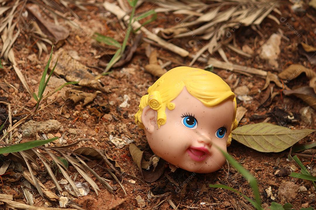 Cabeça de boneca quebrada sobre folhas floresta