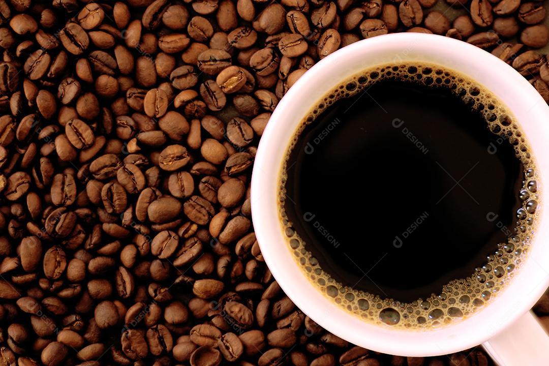 Café dentro de uma xicara sobre grãos de cafe