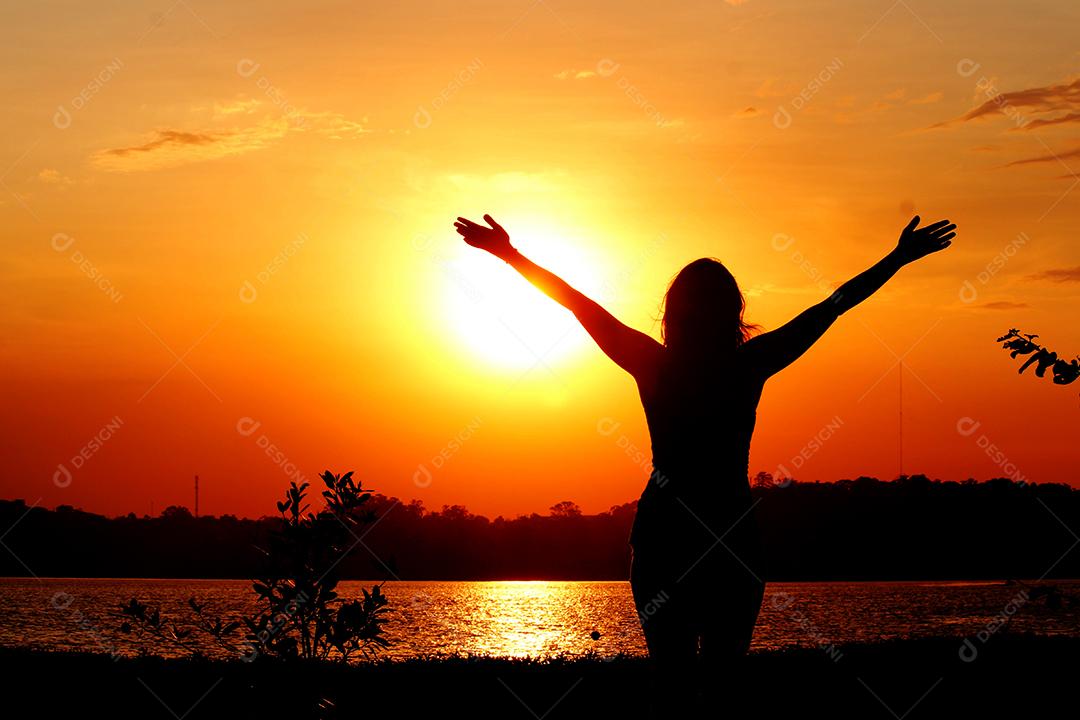 Pessoas de braços abertos frente a praia