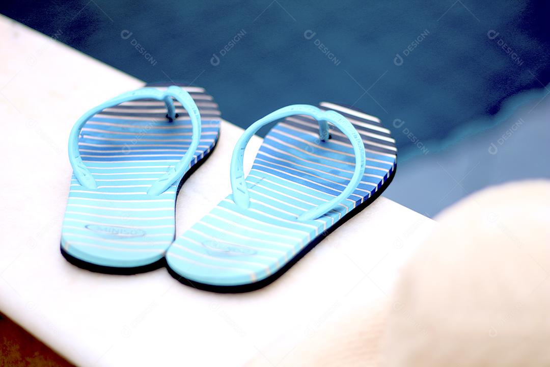 Chinelo listrada sobre beira de piscina