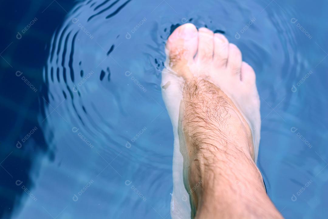 Pés na frente da água azul em uma piscina