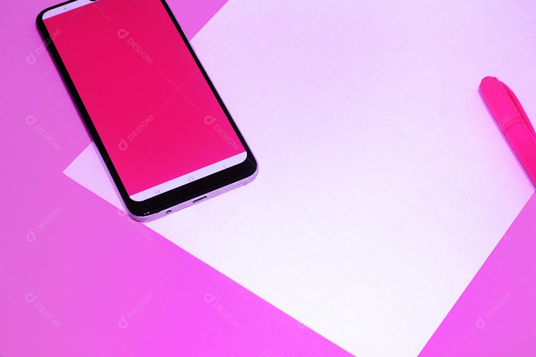 Celular smartphone sobre fundo rosa caneta papel