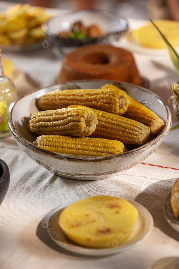 Milho cozido em uma mesa com outros alimentos feitos com milho no fundo desfocado. Culinária nordestina.
