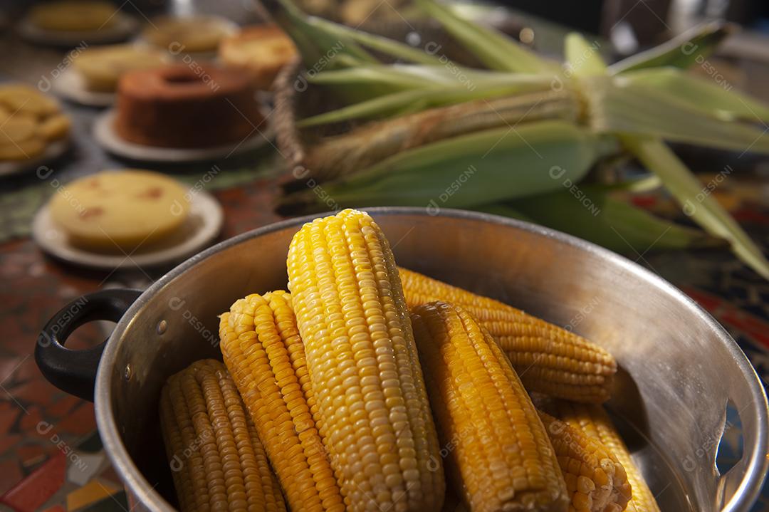 Milho cozido em uma mesa com outros alimentos feitos com milho no fundo desfocado. Culinária nordestina.