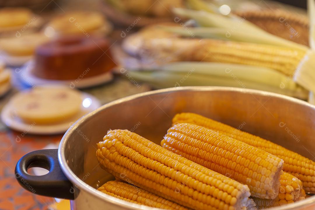 Milho cozido em uma mesa com outros alimentos feitos com milho no fundo desfocado. Culinária nordestina.