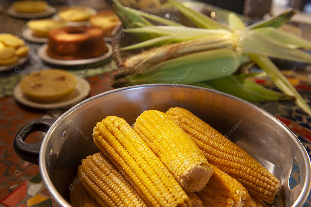 Milho cozido em uma mesa com outros alimentos feitos com milho no fundo desfocado. Culinária nordestina.