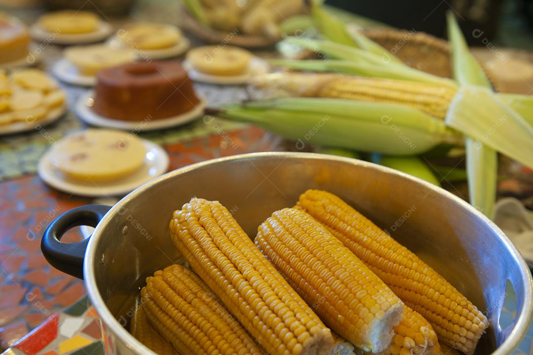 Milho cozido em uma mesa com outros alimentos feitos com milho no fundo desfocado. Culinária nordestina.