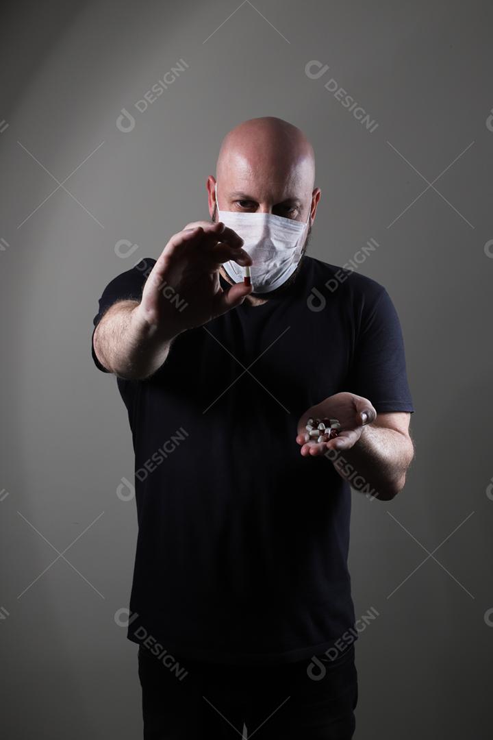 homem careca com camiseta preta usando máscara protetora e segurando