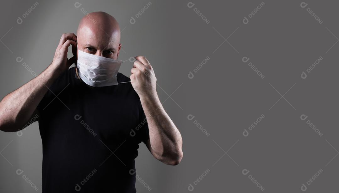 homem careca com camiseta preta usando máscara protetora