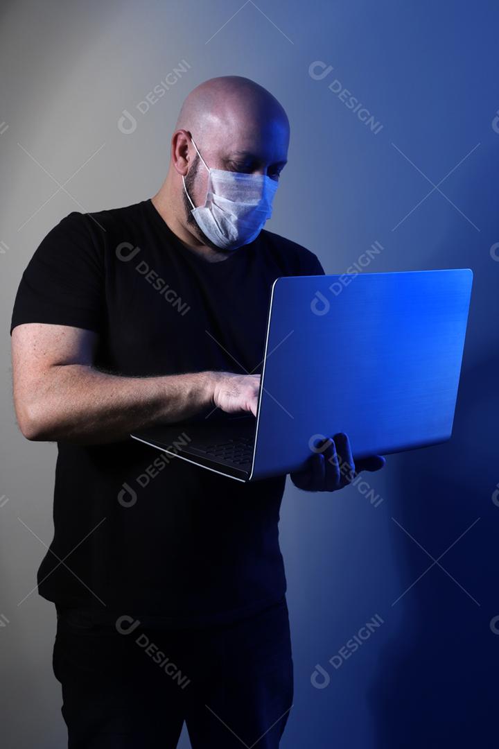 homem careca com camiseta preta usando máscara protetora e segurando