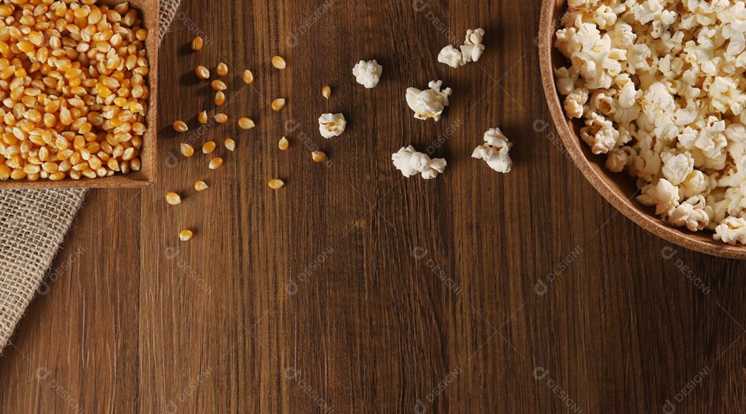 Pipoca e milho em um fundo de madeira. Close-up, vista superior.