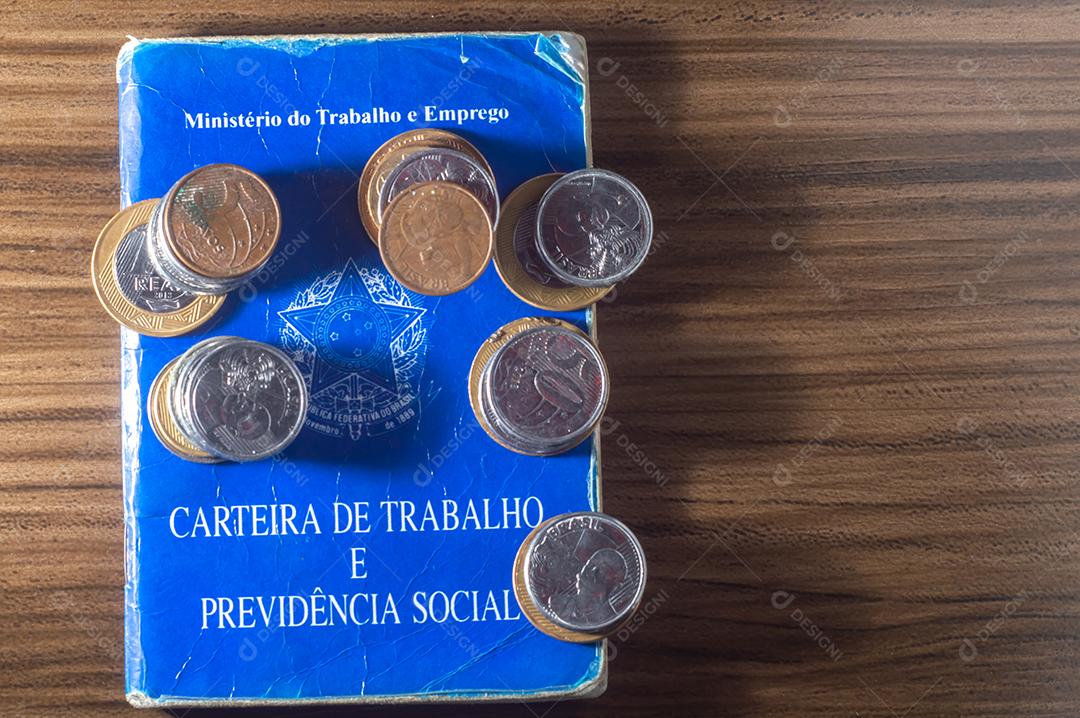 República Federativa do Brasil, Ministério do Trabalho. Carteira de trabalho ao lado de moedas reais brasileiras