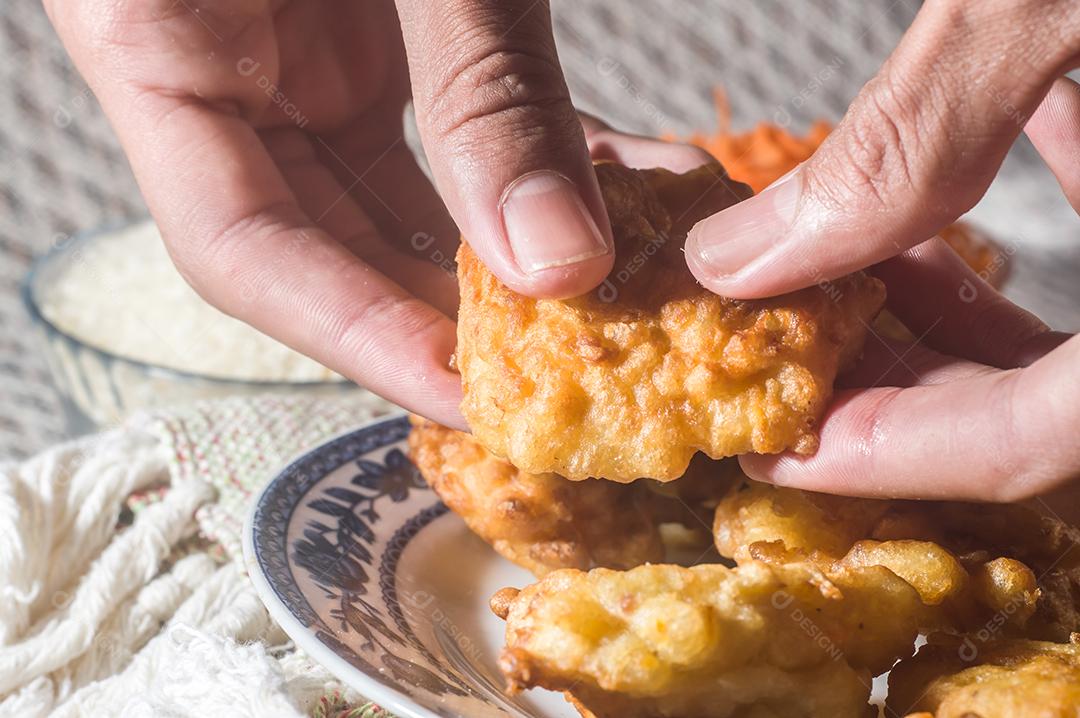 bolinhos de arroz fritos em um prato e fundo listrado, tigela com feijão