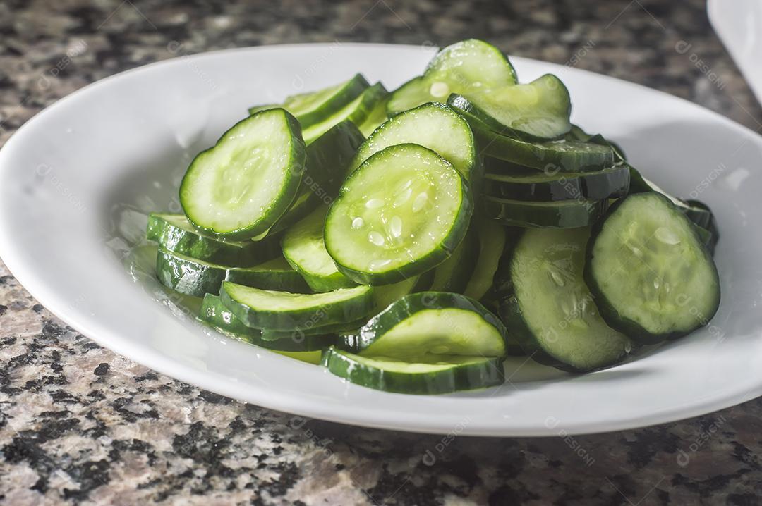 Picles de pepino em um prato branco com fundo escuro