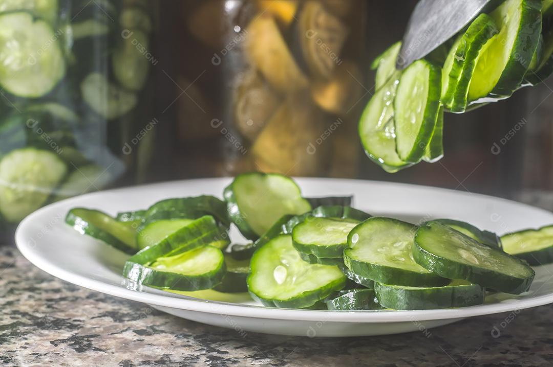 Picles de pepino em um prato branco com fundo escuro
