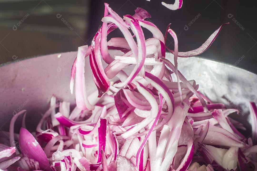 cebola roxa em uma panela de alumínio, rua ao fundo