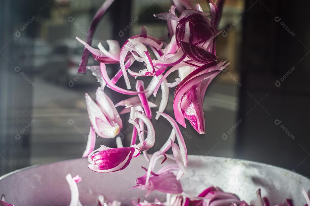 cebola roxa em uma panela de alumínio, rua ao fundo