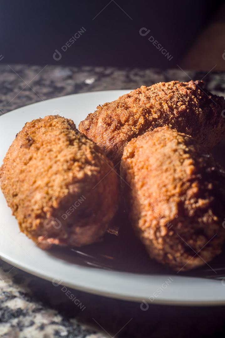 Bolinhos de salsicha com queijo cheddar e em uma placa de aço e mão segurando, fundo escuro