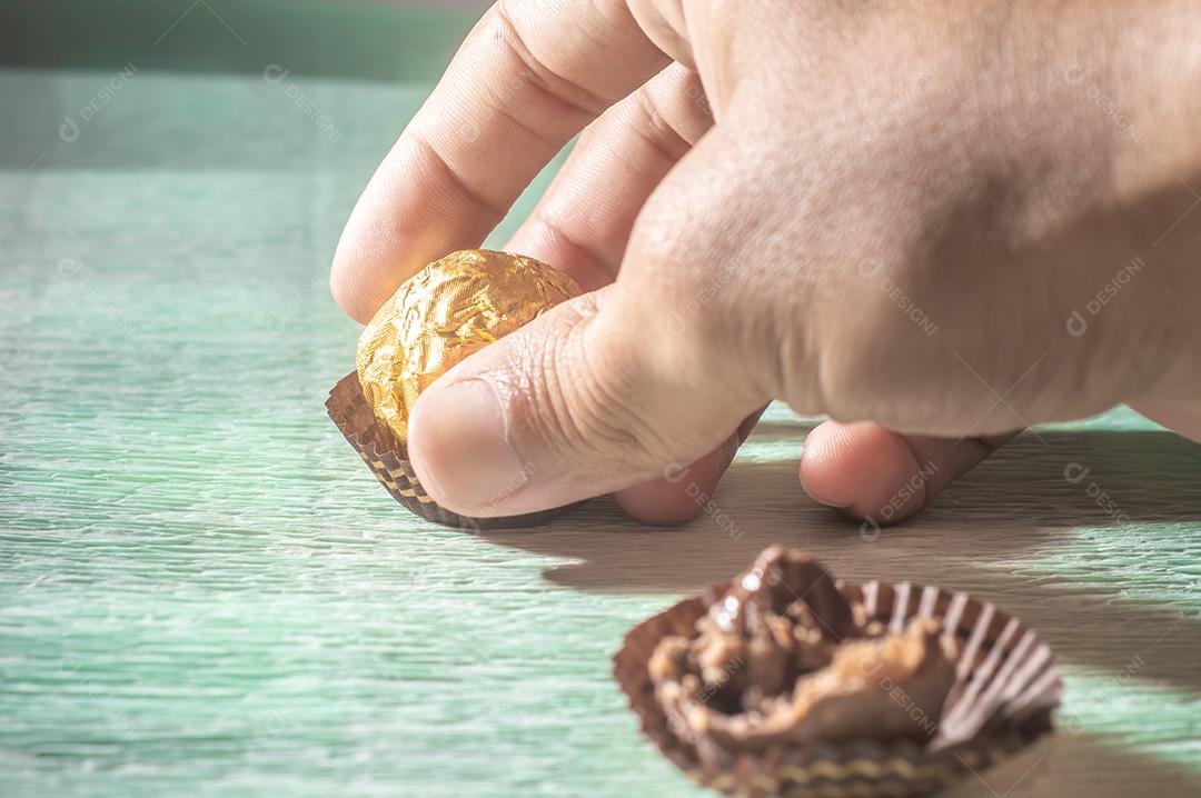 Chocolate com ancoragem dourada em cima de uma toalha verde clara..