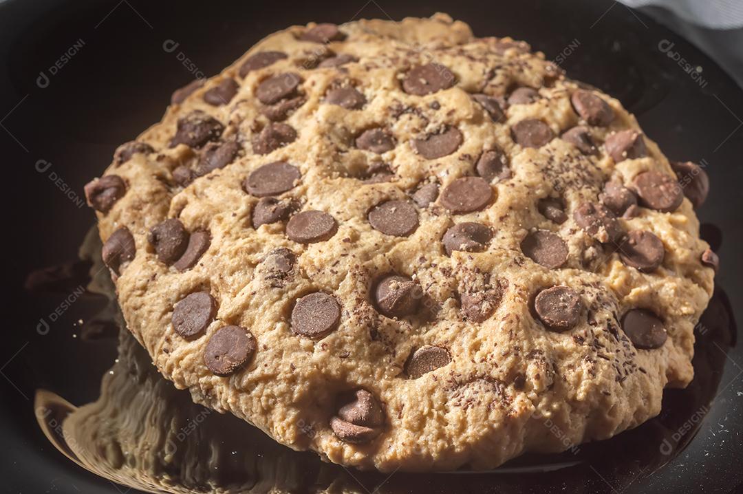 Biscoito grande com gotas de chocolate com luz natural, conceito de receita caseira.