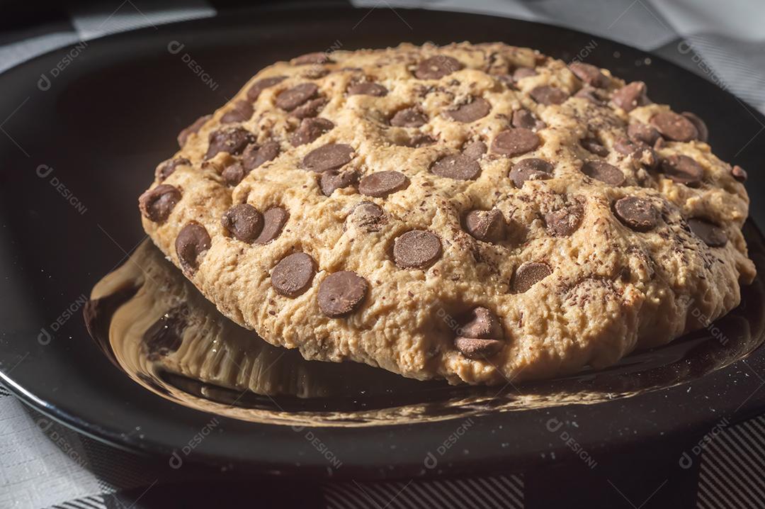 Biscoito grande com gotas de chocolate com luz natural, conceito de receita caseira.