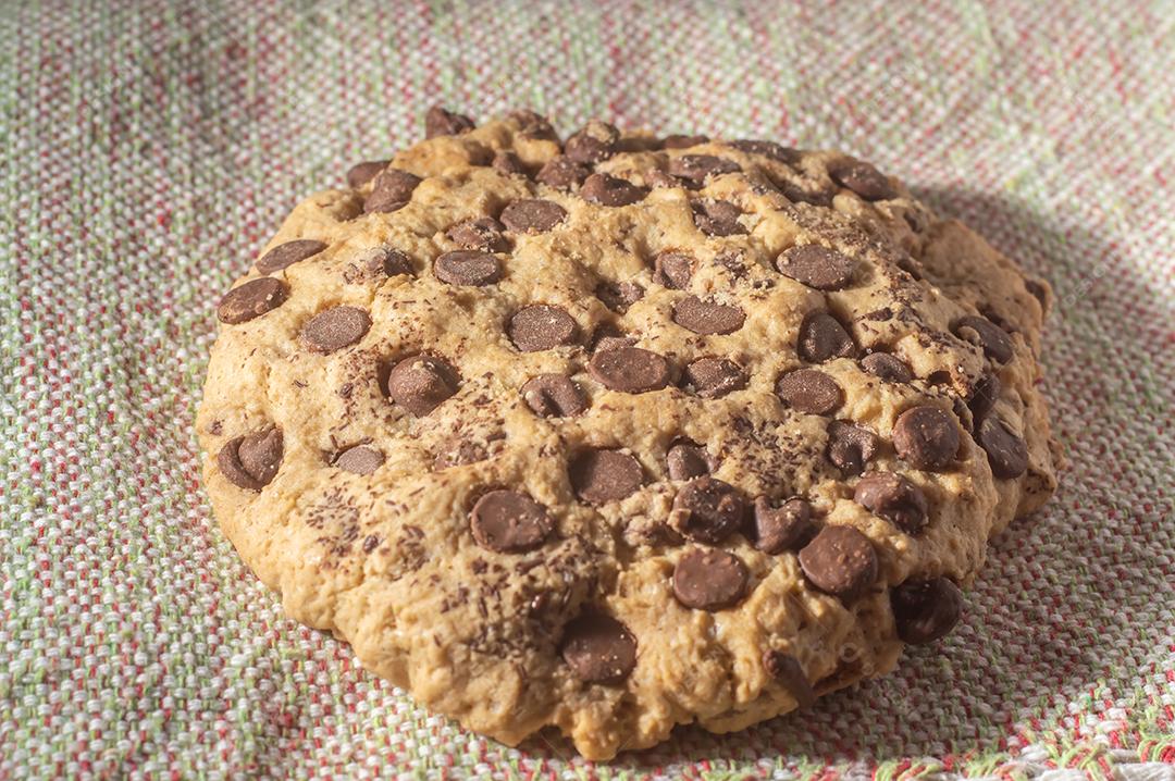 Biscoito grande com gotas de chocolate com luz natural, conceito de receita caseira.