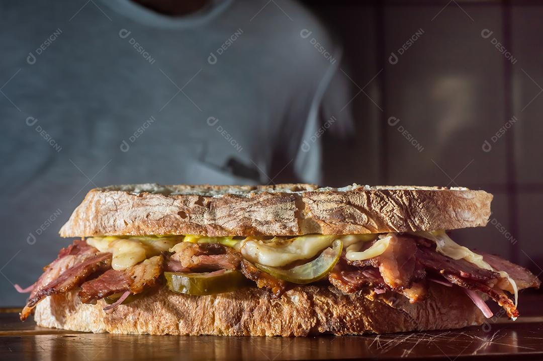 Sandwhich pastrami em uma tábua de madeira com delicioso encontro no pão baguete com queijo