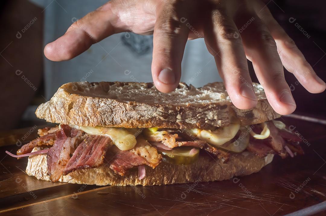 Sandwhich pastrami em uma tábua de madeira com delicioso encontro no pão baguete com queijo