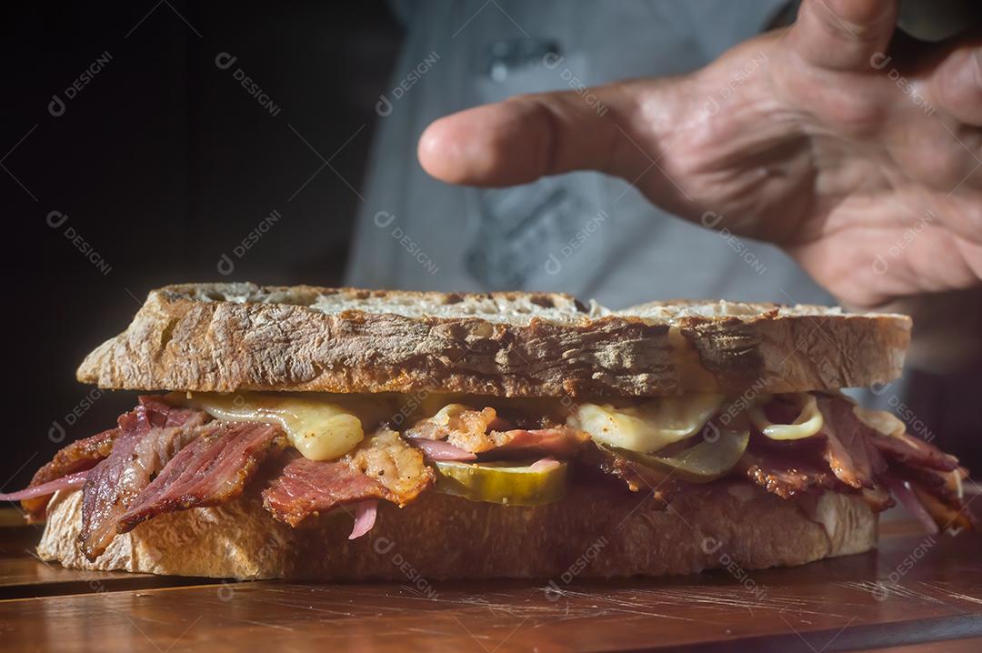 Sandwhich pastrami em uma tábua de madeira com delicioso encontro no pão baguete com queijo