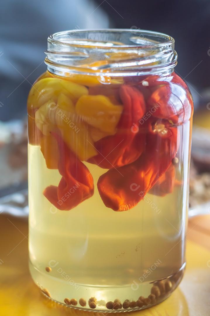 Pimentões amarelos enlatados em uma jarra em fundo de madeira, luz natural.