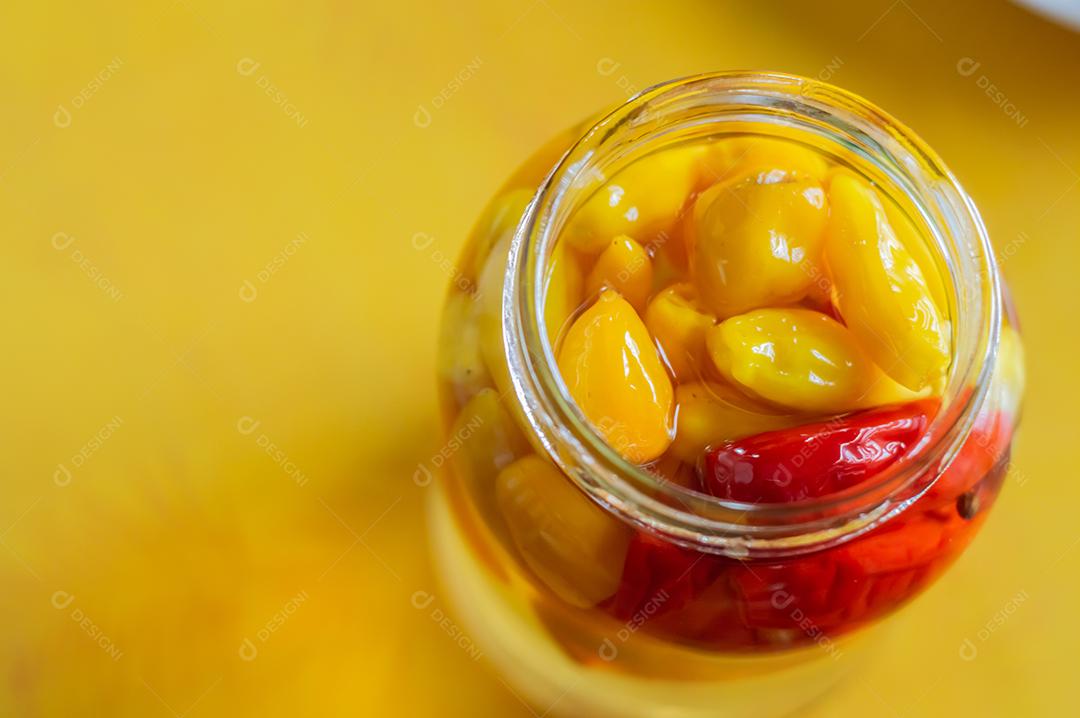 Pimentões amarelos enlatados em uma jarra em fundo de madeira, luz natural.