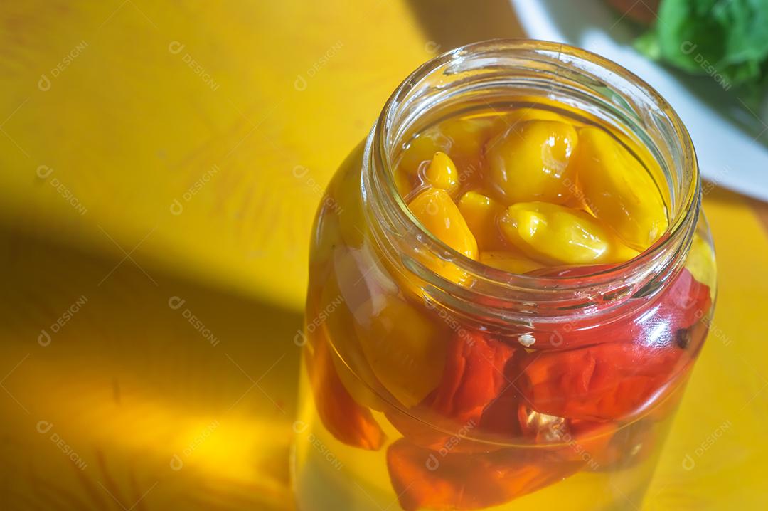 Pimentões amarelos enlatados em uma jarra em fundo de madeira, luz natural.