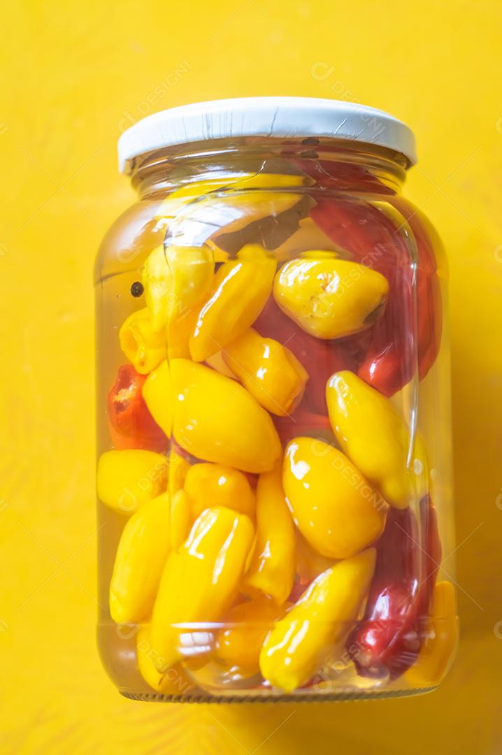 Pimentões amarelos enlatados em uma jarra em fundo de madeira, luz natural.