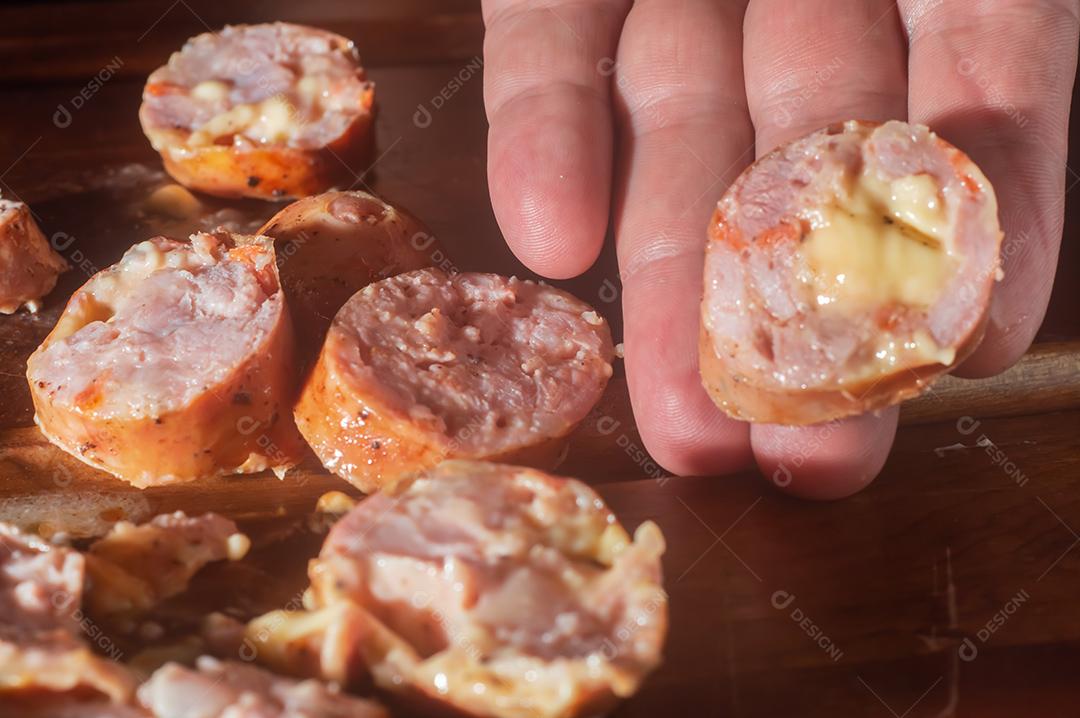 Salsicha cortada em uma mesa de madeira, feita com queijo e pedaços de calabresa italiana