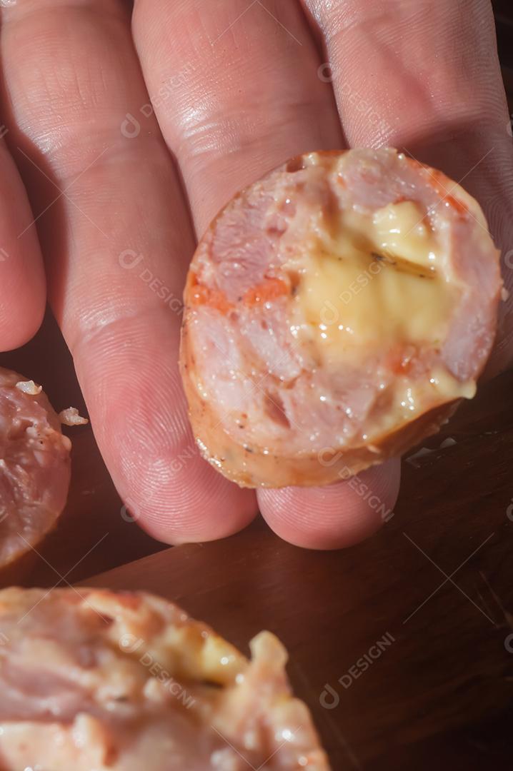 Salsicha cortada em uma mesa de madeira, feita com queijo e pedaços de calabresa italiana