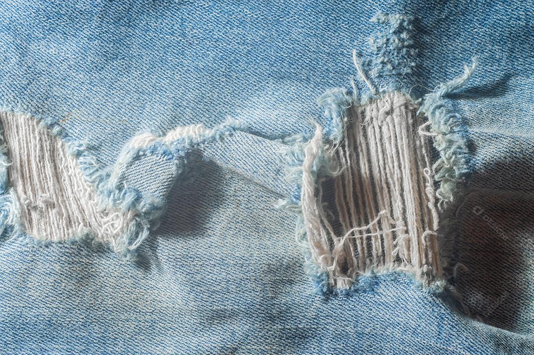 Destruiu a textura de jeans azul rasgado. Fundo de pano azul jeans rasgado. Reciclagem de jeans velho