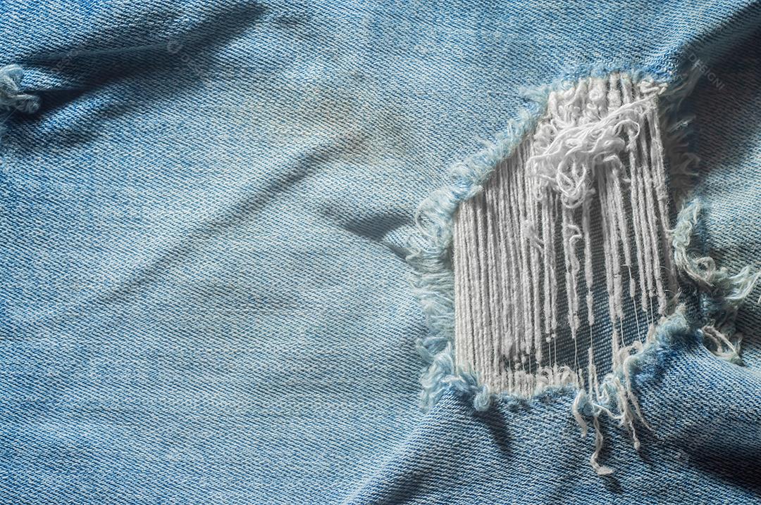 Destruiu a textura de jeans azul rasgado. Fundo de pano azul jeans rasgado. Reciclagem de jeans velho