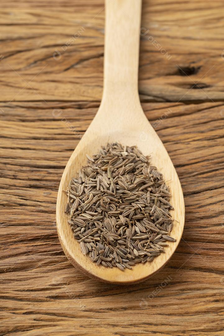 Closeup de sementes de cominho em uma colher de pau. Cenário de comida