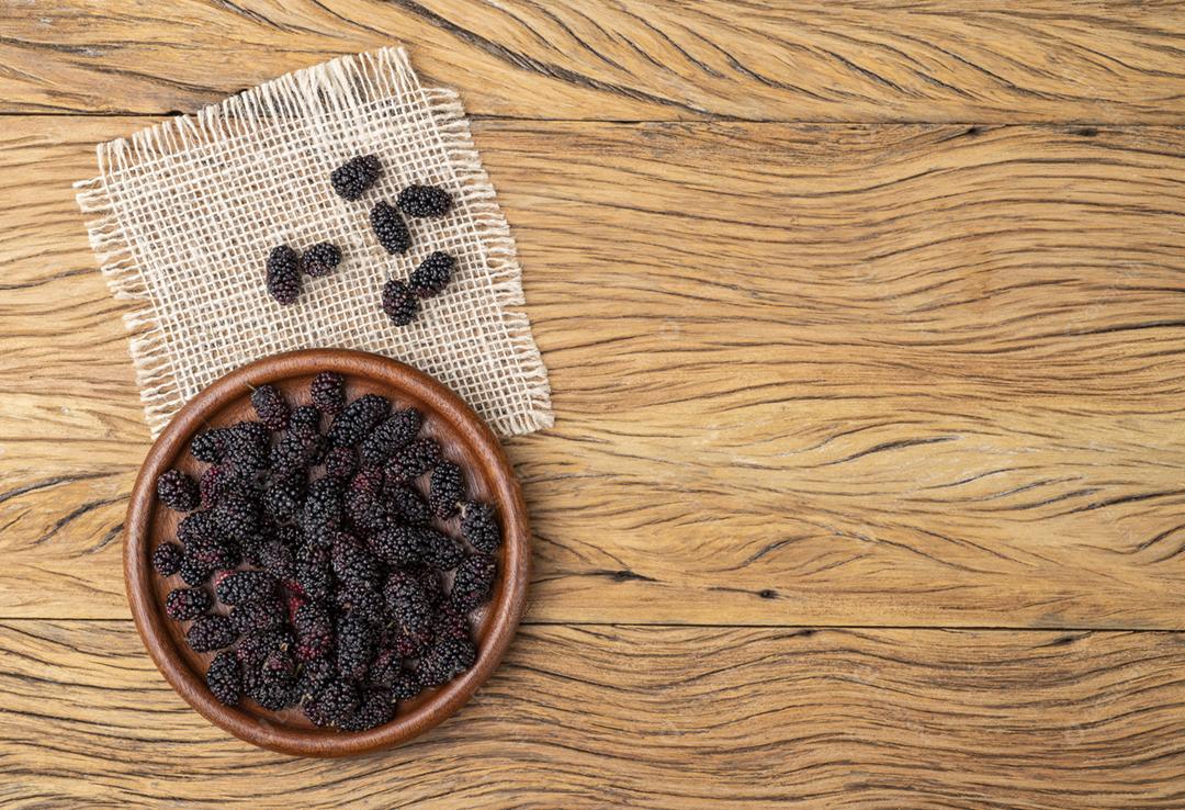 Amoras em um prato sobre mesa de madeira com espaço de cópia
