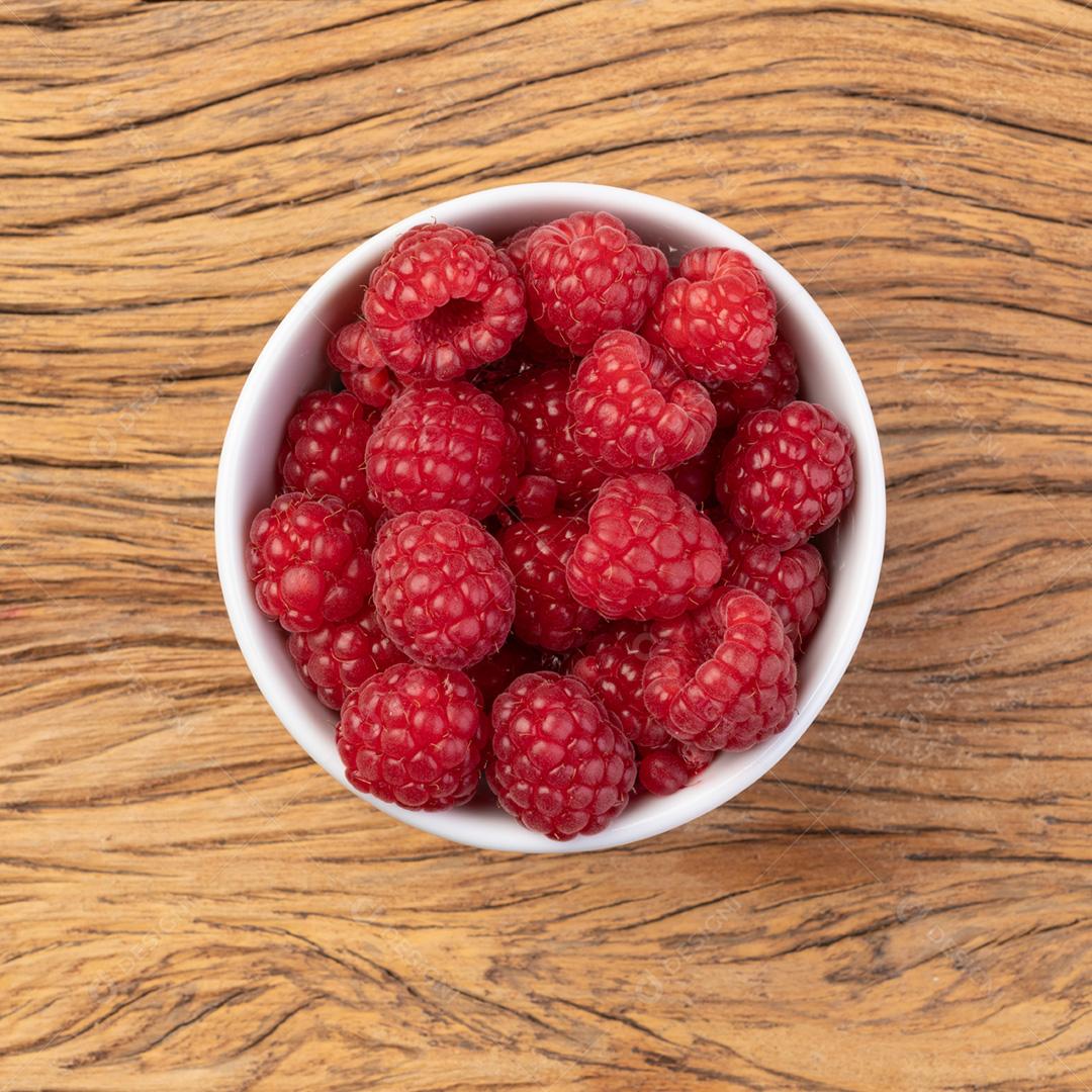 Framboesas em uma tigela sobre a mesa de madeira