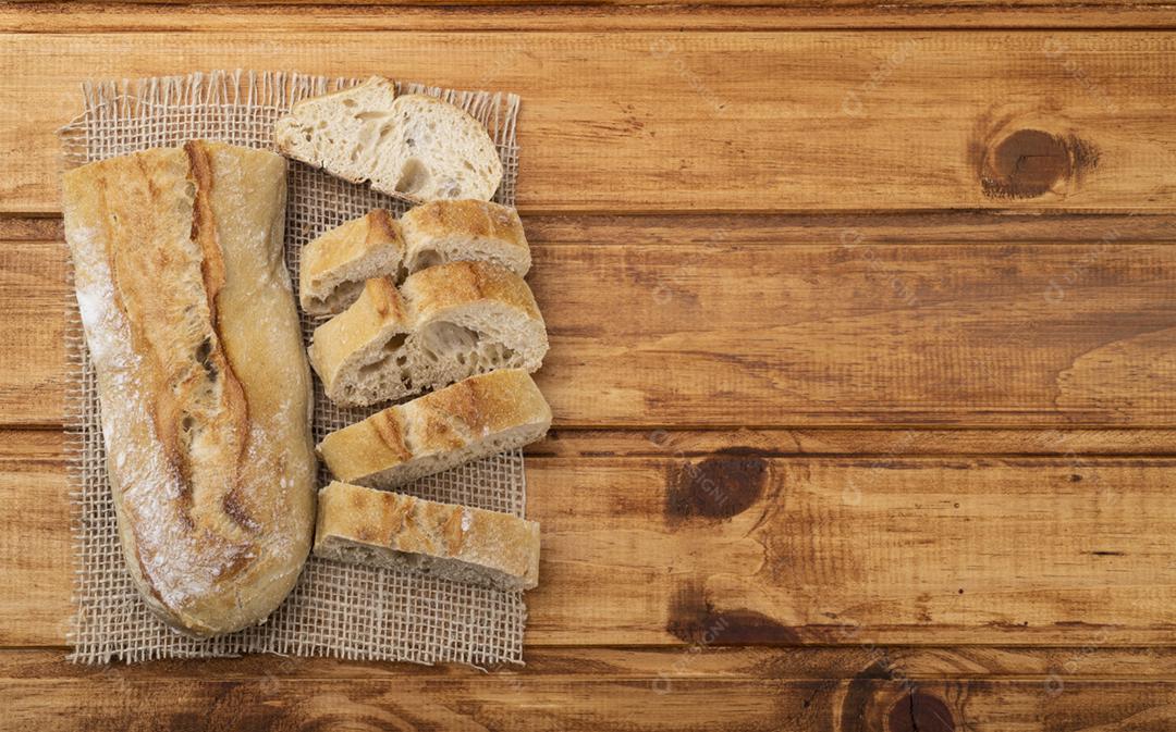Pão de baguete francês caseiro tradicional com fatias sobre madeira