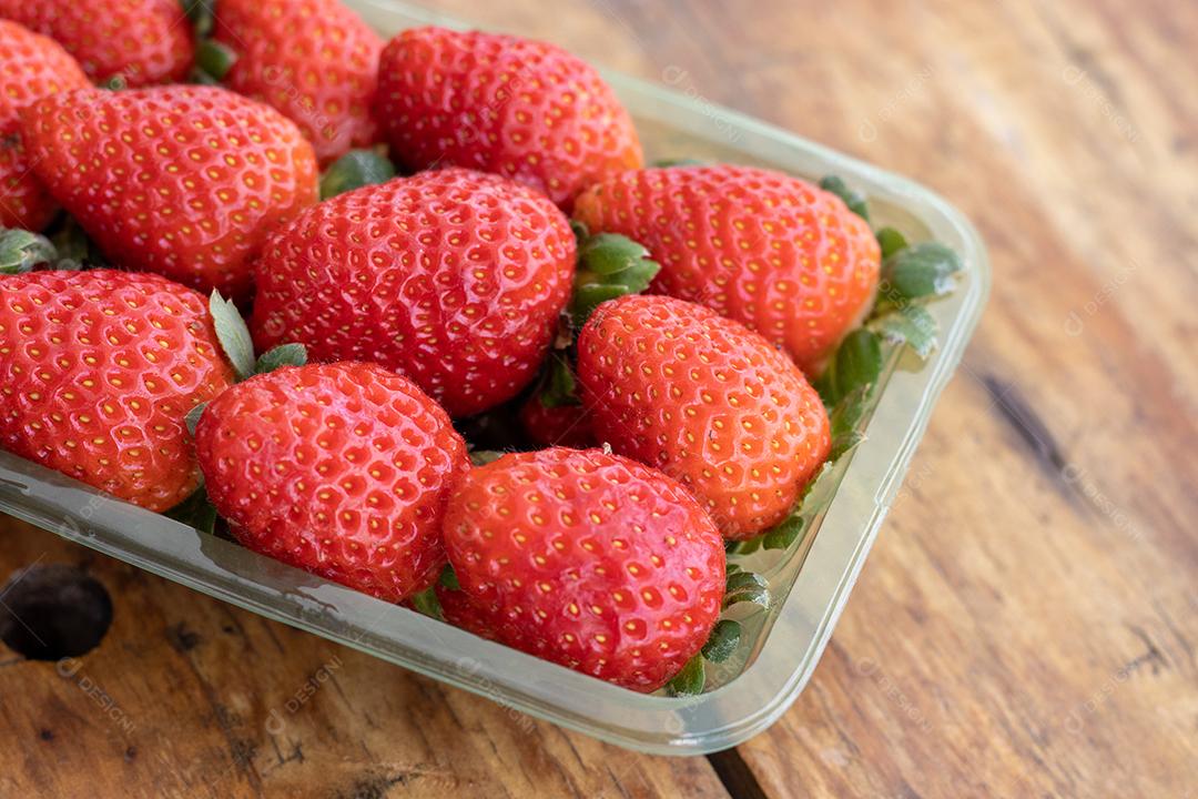 Forma cheia de morangos vermelho sobre mesa de madeira
