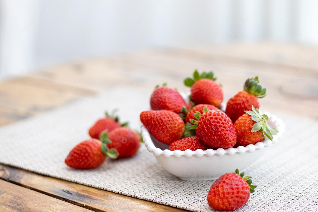 Vários morangos vermelho sobre a mesa uma tijela