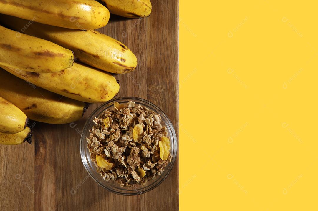 banquete de bananas amarelas maduras em fundo de madeira com cereais